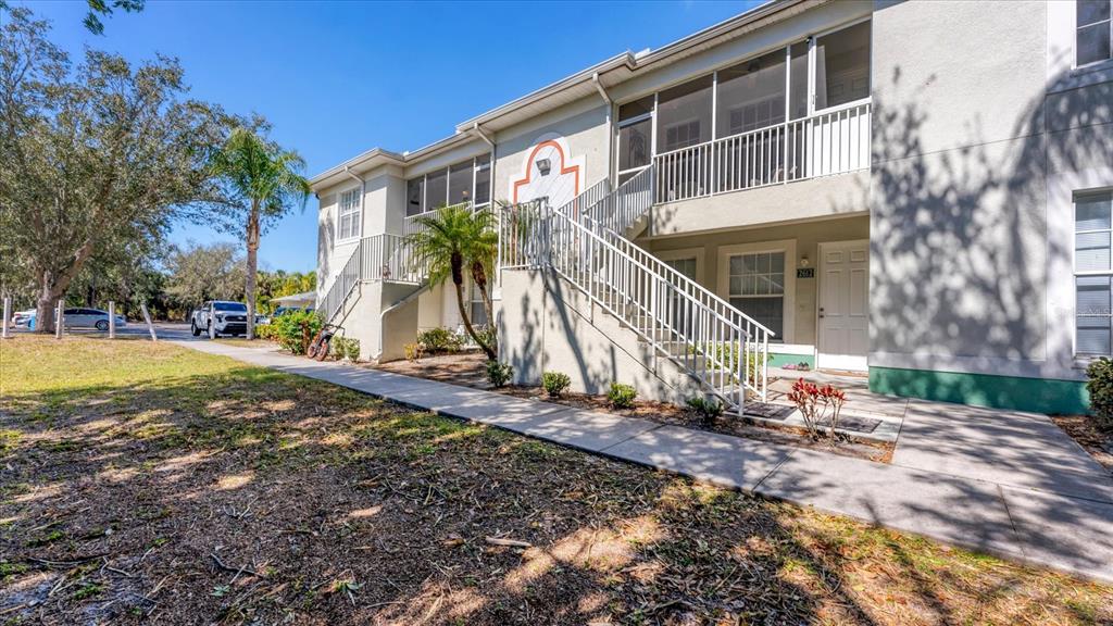 A two-story apartment building exterior features a white staircase leading to a screened balcony — 2628 RIVER PRESERVE COURT UNIT 2628, BRADENTON, FL