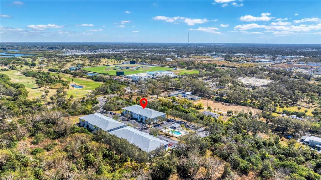 An aerial view shows two multi-story apartment buildings surrounded by trees and a parking lot — 2628 RIVER PRESERVE COURT UNIT 2628, BRADENTON, FL