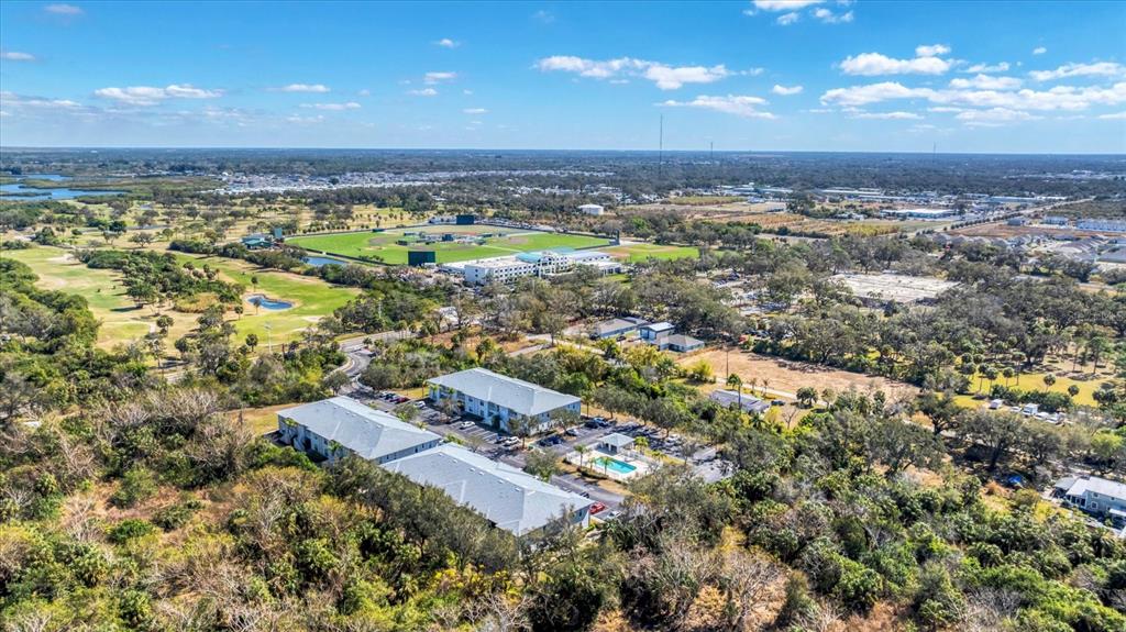 An aerial view shows two apartment buildings with a pool surrounded by trees and fields — 2628 RIVER PRESERVE COURT UNIT 2628, BRADENTON, FL