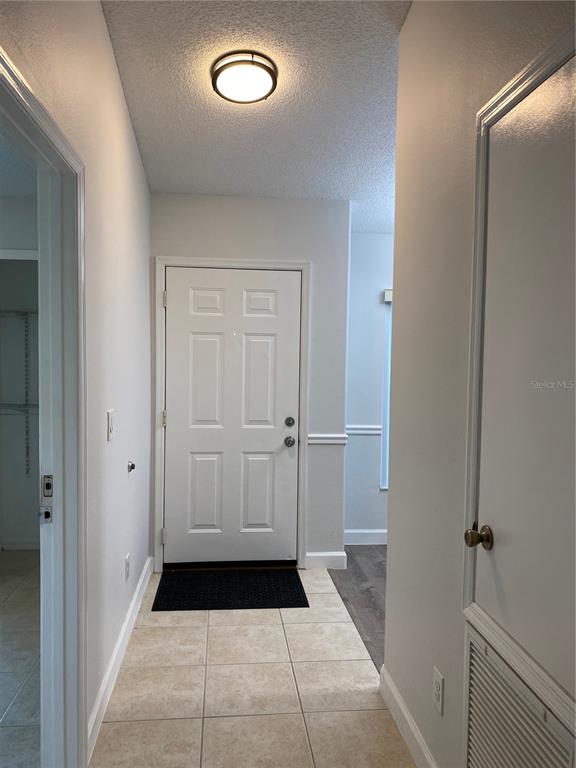An entryway features a white door, tile flooring, and a ceiling-mounted light fixture — 13724 RIVERPATH GROVE DRIVE, ORLANDO, FL