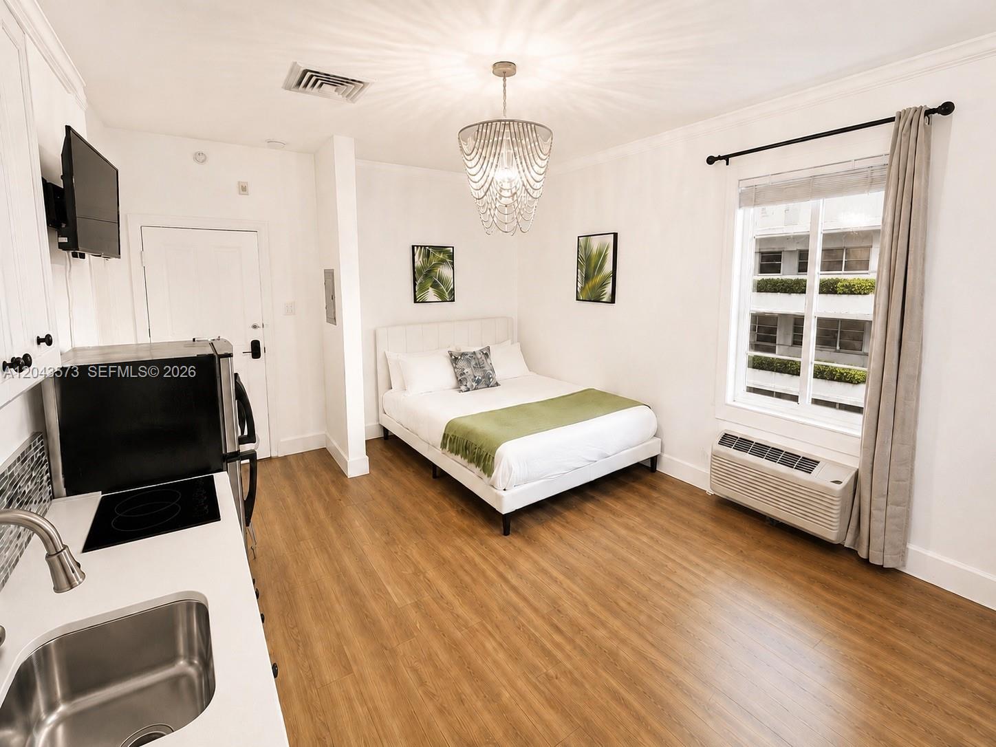 A studio apartment features a kitchenette, a bed, and a window with a view — 3025 Indian Creek Dr # 322, Miami Beach FL 33140, MIAMI BEACH, FL