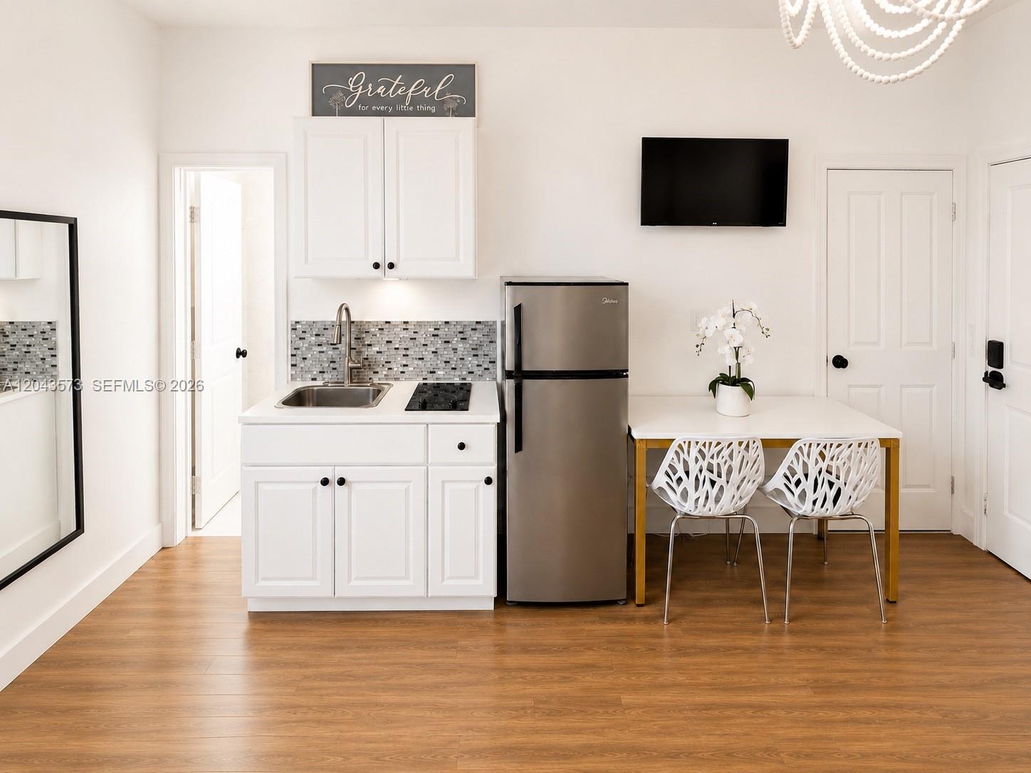 A small kitchen area features white cabinets, a stainless steel refrigerator, and a dining table — 3025 Indian Creek Dr # 322, Miami Beach FL 33140, MIAMI BEACH, FL