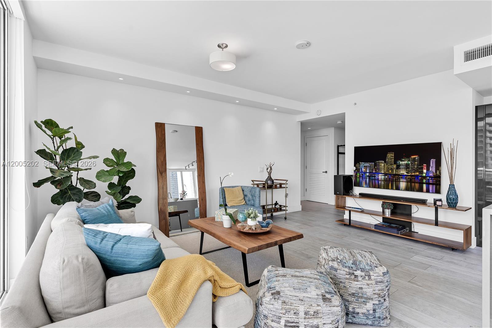 A modern living room features a light gray sofa, wooden coffee table, and wall-mounted television — 1080 Brickell Ave # 2601, Miami FL 33131, MIAMI, FL