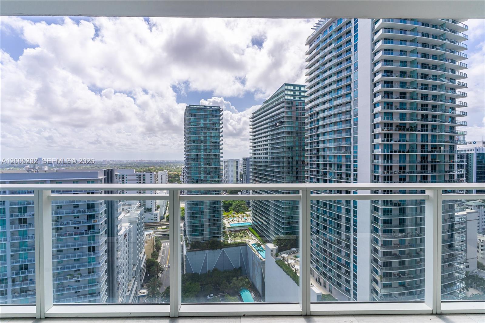 A high-rise balcony overlooks a dense urban landscape of modern glass skyscrapers and streets — 1080 Brickell Ave # 2601, Miami FL 33131, MIAMI, FL