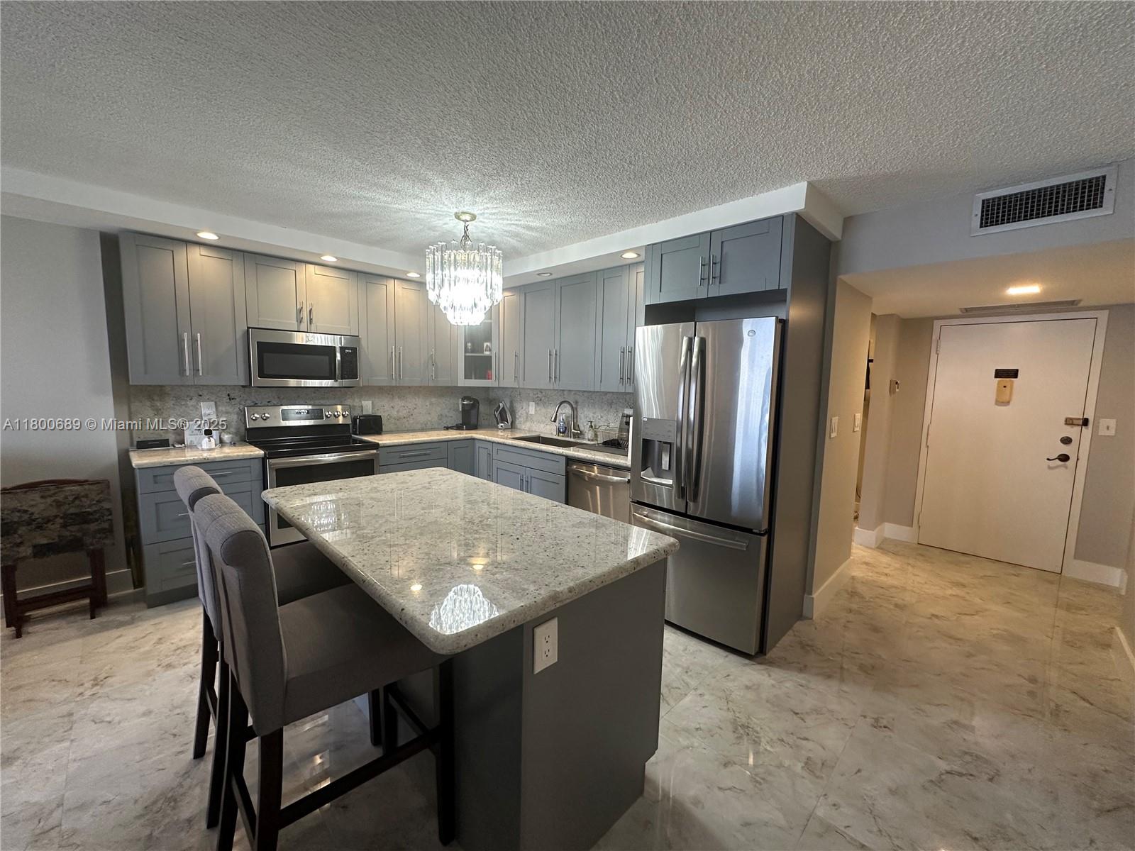A modern kitchen features gray cabinetry, granite countertops, stainless steel appliances, and a central island — 1865 S Ocean Dr # 17C, Hallandale Beach FL 33009, HALLANDALE BEACH, FL