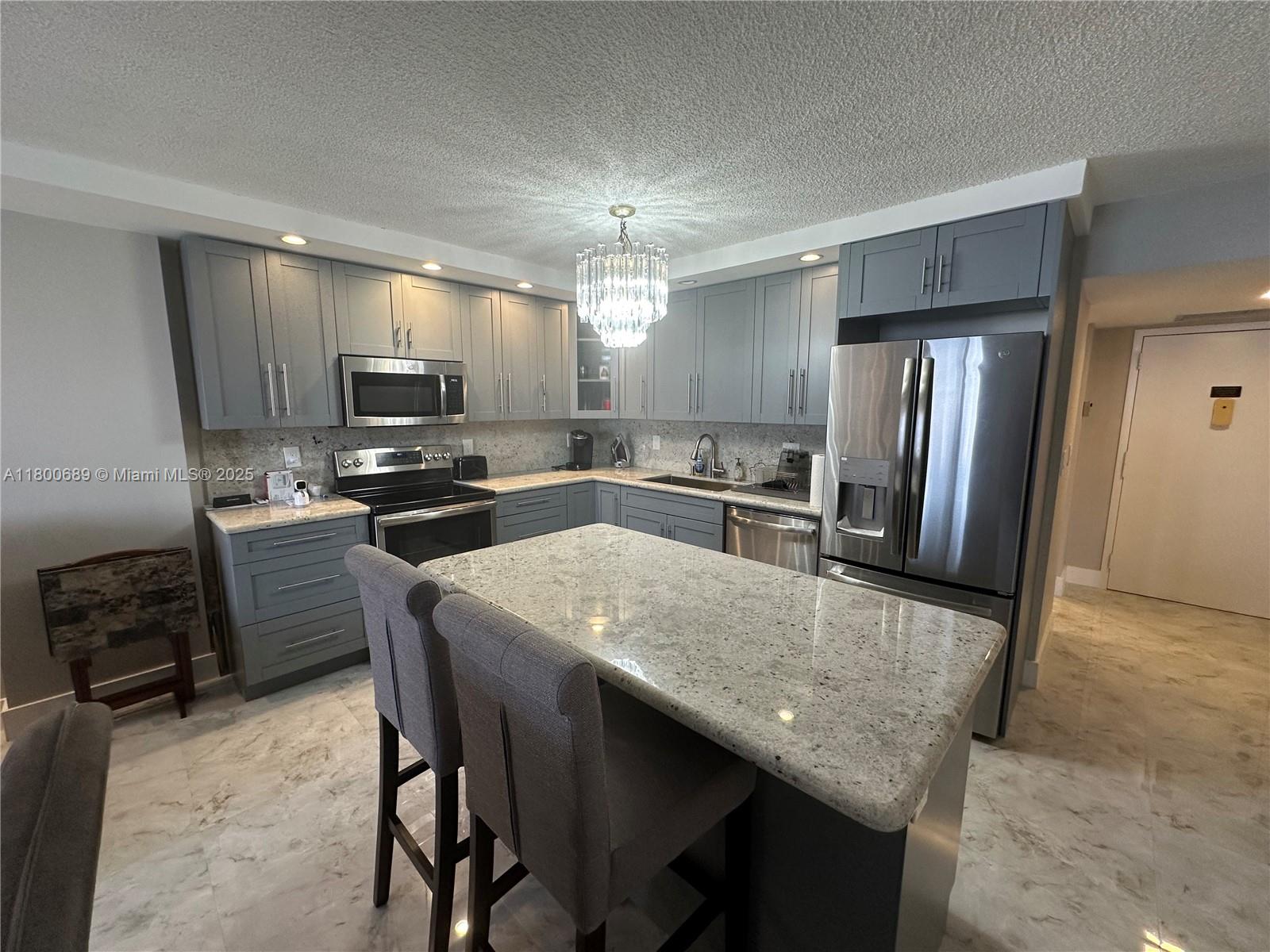 A kitchen features gray cabinets, granite countertops, stainless steel appliances, and a central island — 1865 S Ocean Dr # 17C, Hallandale Beach FL 33009, HALLANDALE BEACH, FL