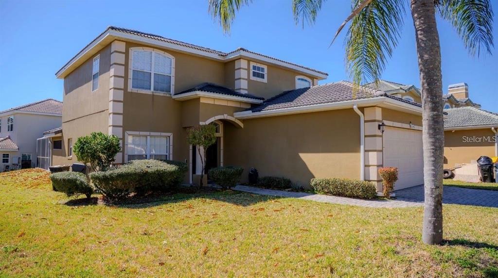A two-story tan stucco house with a tiled roof and a paved driveway — 416 VISTA LOOP, DAVENPORT, FL