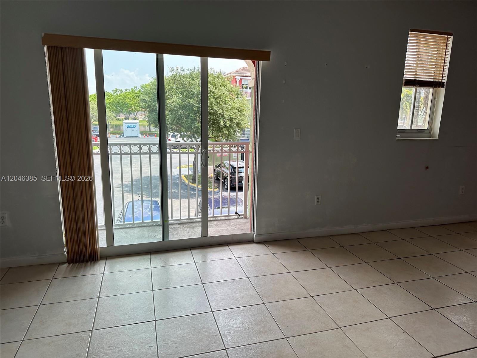 A room with beige tile flooring, a sliding glass door, and a small window — 11002 NW 83rd St # 215, Doral FL 33178, DORAL, FL