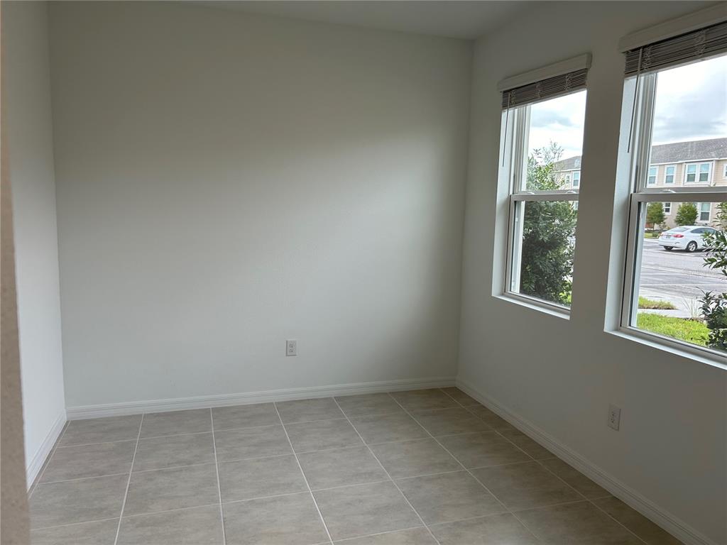 An empty room with light-colored tile flooring, white walls, and two windows overlooking a street — 6156 WHETSTONE COURT, PALMETTO, FL