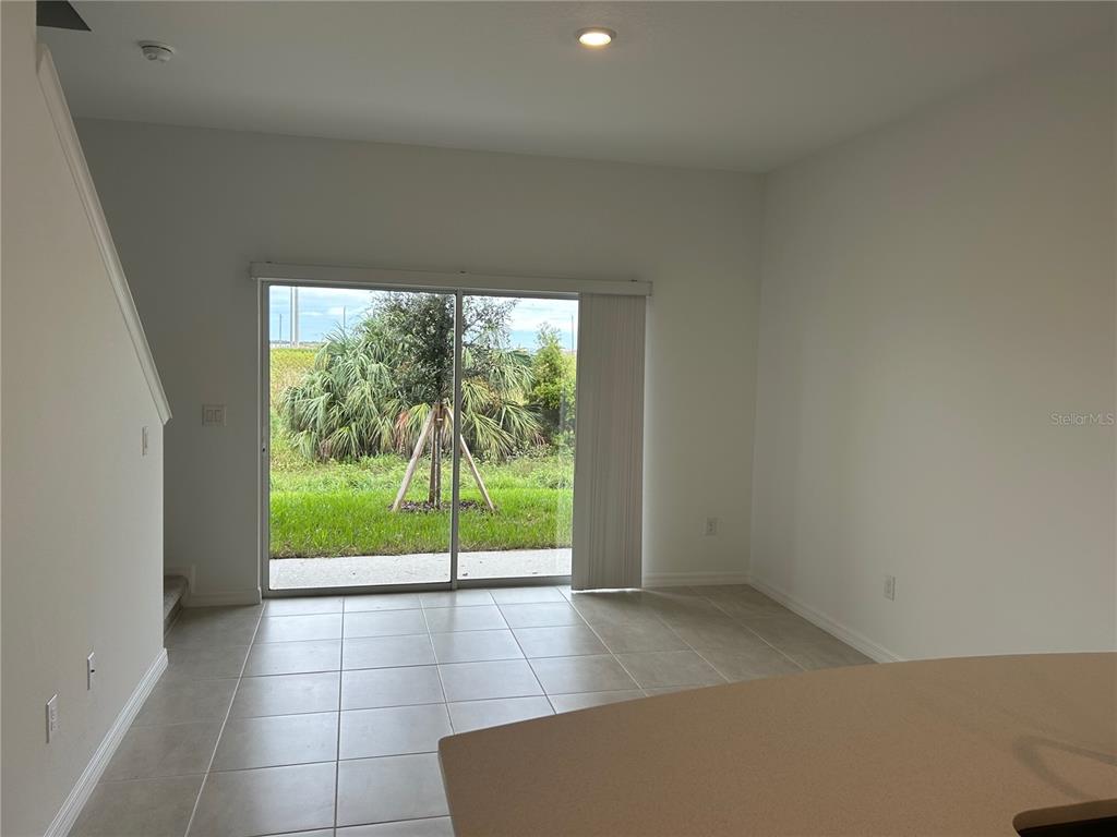 A bright room with light tile flooring, a sliding glass door, and a staircase — 6156 WHETSTONE COURT, PALMETTO, FL