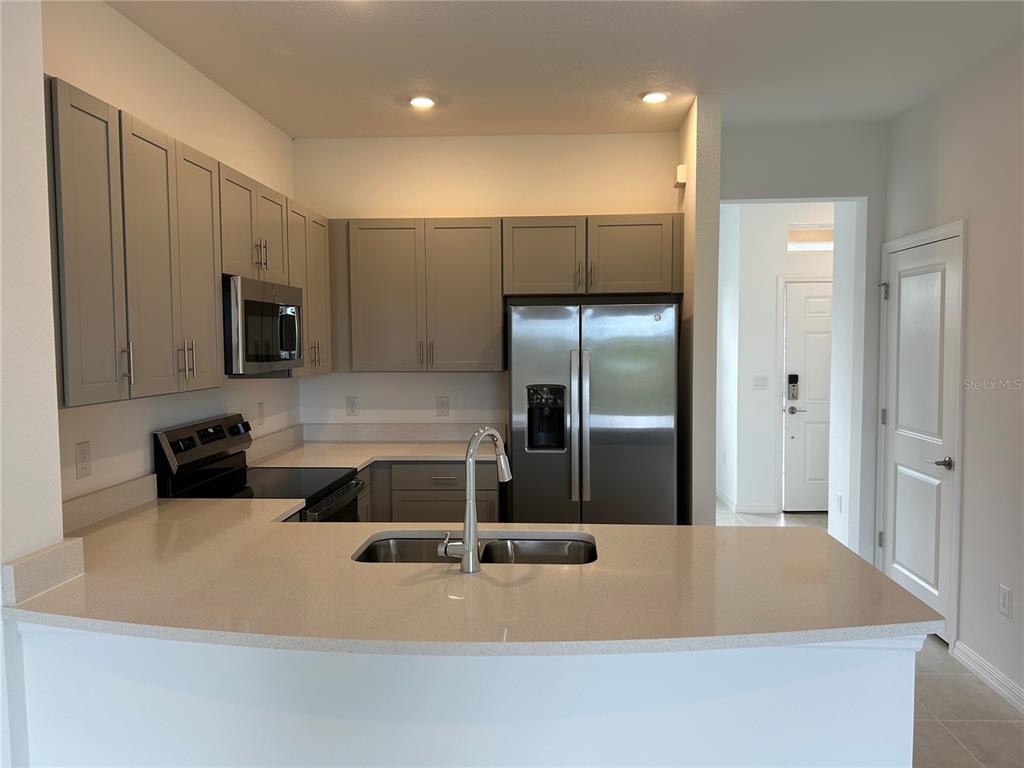 A kitchen features gray cabinets, stainless steel appliances, and a peninsula with a double sink — 6156 WHETSTONE COURT, PALMETTO, FL