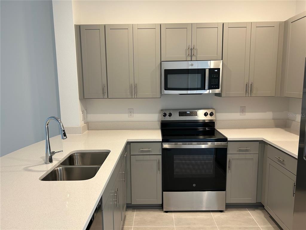 A kitchen features gray cabinets, stainless steel appliances, and white countertops — 6156 WHETSTONE COURT, PALMETTO, FL