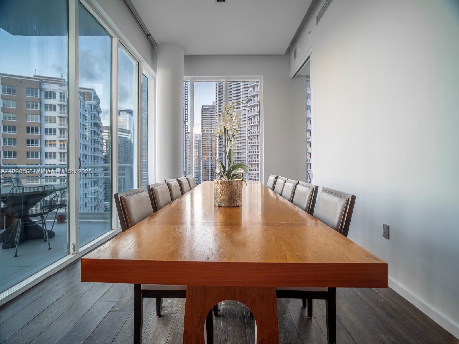 A long wooden dining table sits in a room with floor-to-ceiling windows and city views — 900 Brickell Key Blvd # 2204, Miami FL 33131, MIAMI, FL