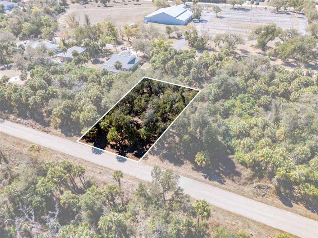 An aerial view shows a rectangular, wooded plot of land outlined in white beside a road — 397 KEZAR STREET, PORT CHARLOTTE, FL