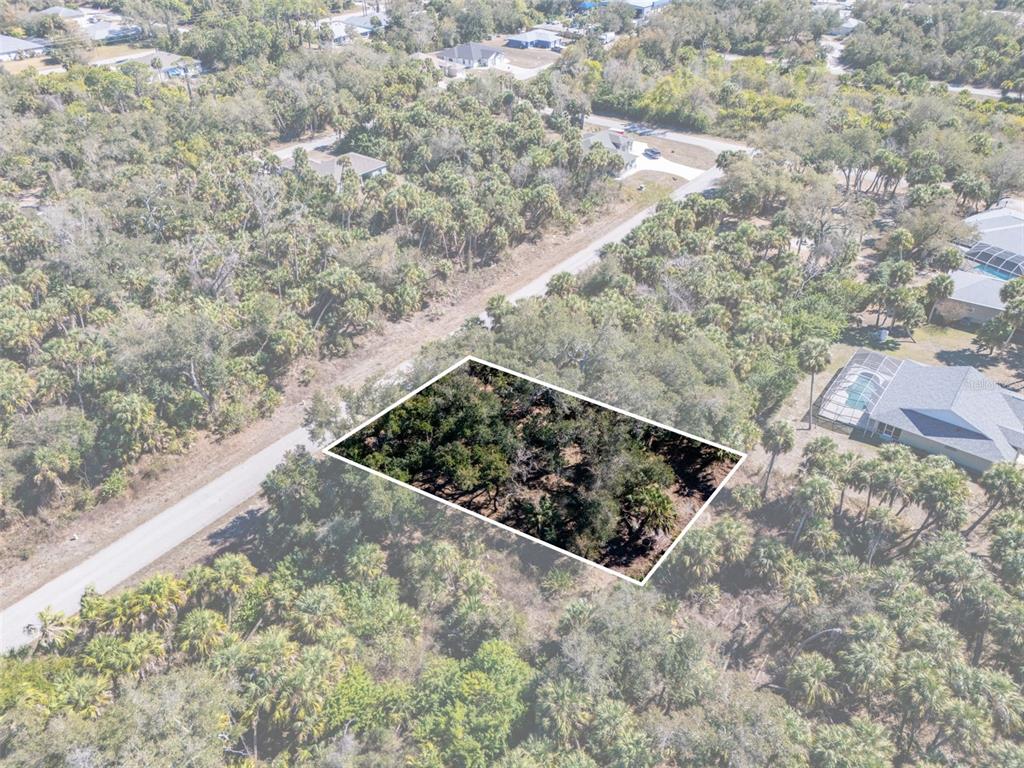 An aerial view shows a rectangular wooded lot outlined in white next to a road — 397 KEZAR STREET, PORT CHARLOTTE, FL