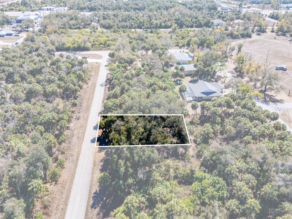 An aerial view shows a rectangular wooded lot adjacent to a paved road — 397 KEZAR STREET, PORT CHARLOTTE, FL