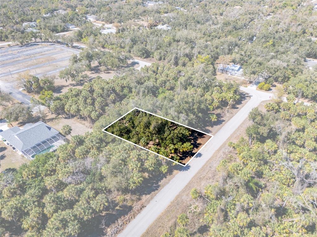 An aerial view shows a rectangular, wooded vacant lot outlined in white next to a road — 397 KEZAR STREET, PORT CHARLOTTE, FL