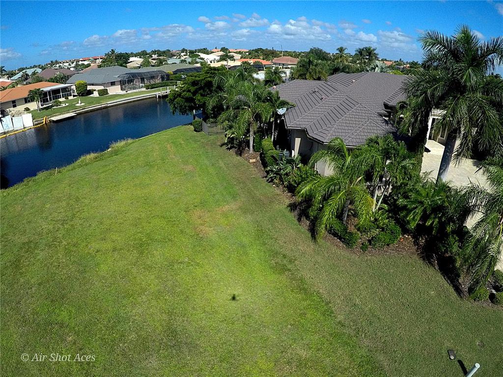 An aerial view shows a house with a tile roof next to a canal and lawn — 631 COMO COURT, PUNTA GORDA, FL