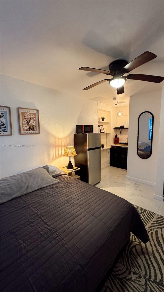 A bedroom features a bed, a small kitchenette area, a refrigerator, and a ceiling fan — 460 NW 109th St, Miami FL 33168, MIAMI, FL