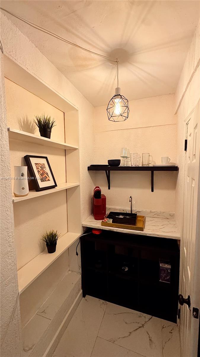 A small wet bar area features open shelving, a marble countertop, and a pendant light — 460 NW 109th St, Miami FL 33168, MIAMI, FL