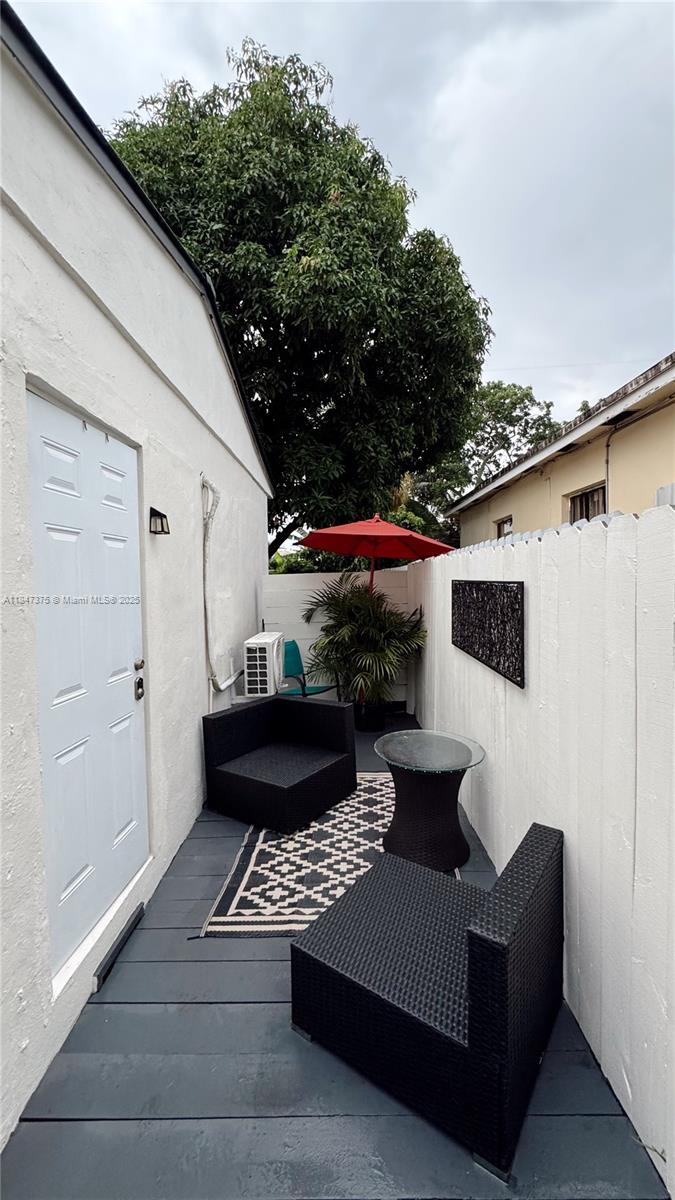 A small outdoor patio features black wicker furniture, a patterned rug, and a red umbrella — 460 NW 109th St, Miami FL 33168, MIAMI, FL