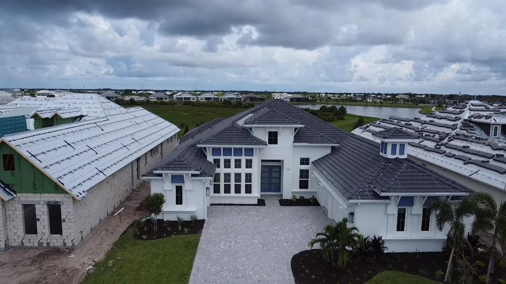 An aerial view of a modern white house with a dark tiled roof and driveway — 17483 MONTGOMERY COURT, VENICE, FL