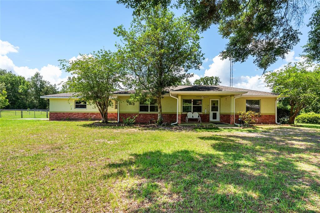 A single-story house with a brick base, light-colored siding, and a covered front porch — 7360 SW 15TH PLACE, OCALA, FL