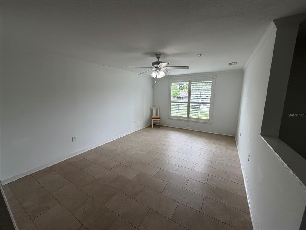 An empty room features light-colored walls, a ceiling fan, and large rectangular floor tiles — 110 OLIVE TREE CIRCLE UNIT 110, ALTAMONTE SPRINGS, FL