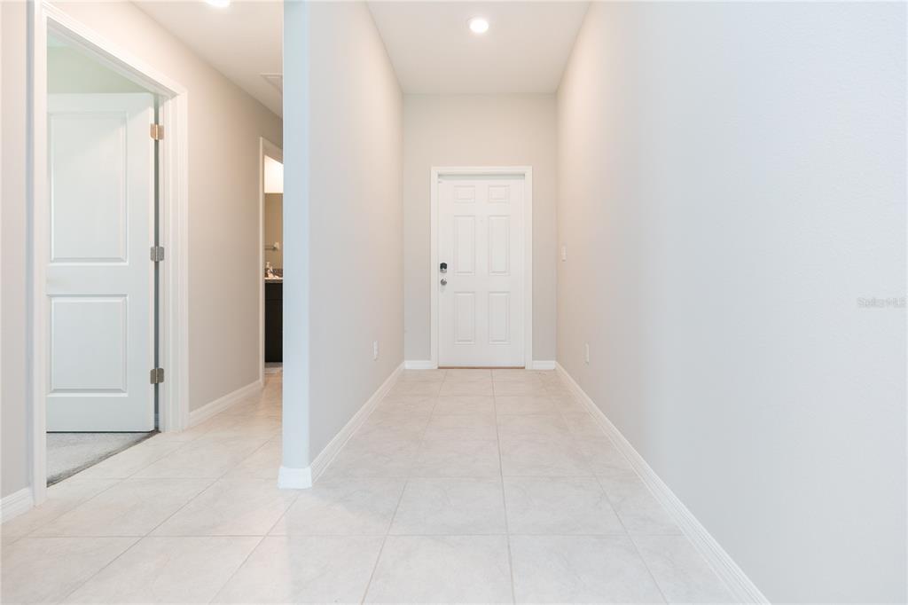 A tiled entryway features a white front door and a doorway leading to a bathroom — 13608 WILLOW BLUESTAR LOOP, RIVERVIEW, FL