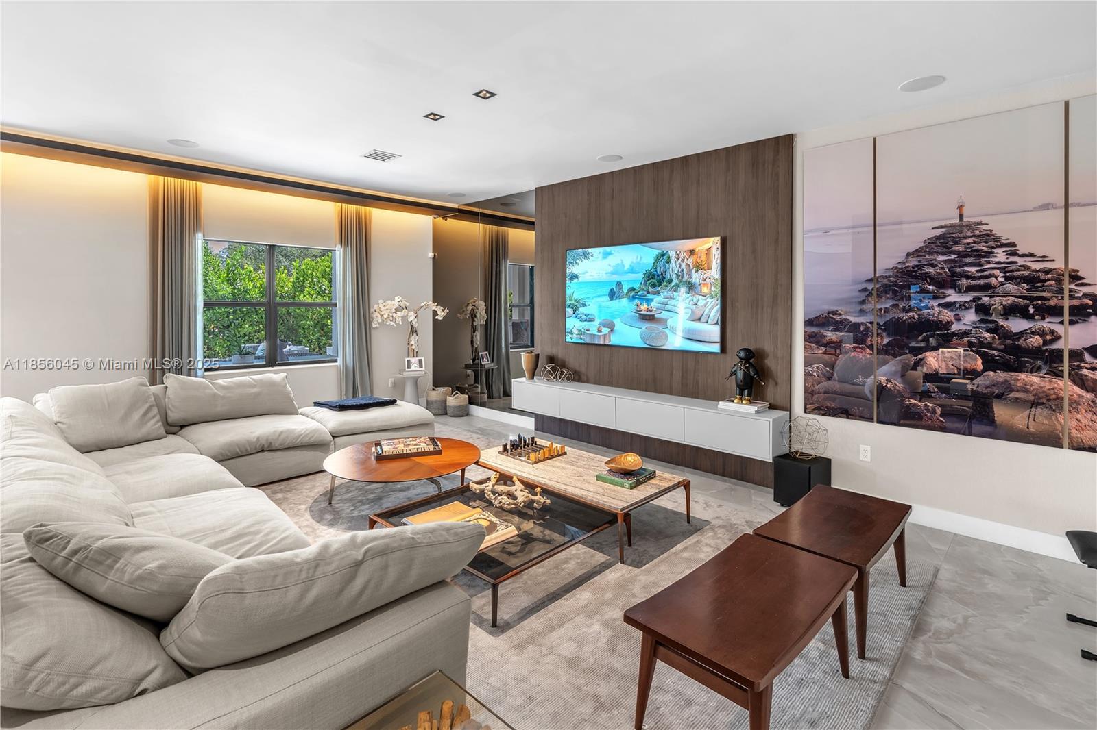 A modern living room features a large sectional sofa, a wall-mounted television, and wood paneling — 4335 SW 173rd Ave, Miramar FL 33029, MIRAMAR, FL