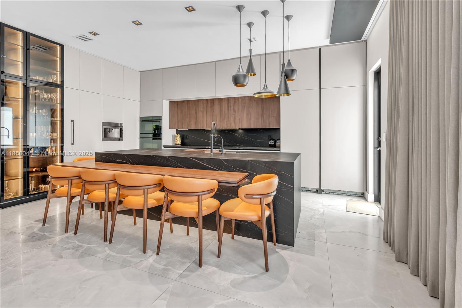A modern kitchen features a large black stone island with orange chairs and wood cabinetry — 4335 SW 173rd Ave, Miramar FL 33029, MIRAMAR, FL