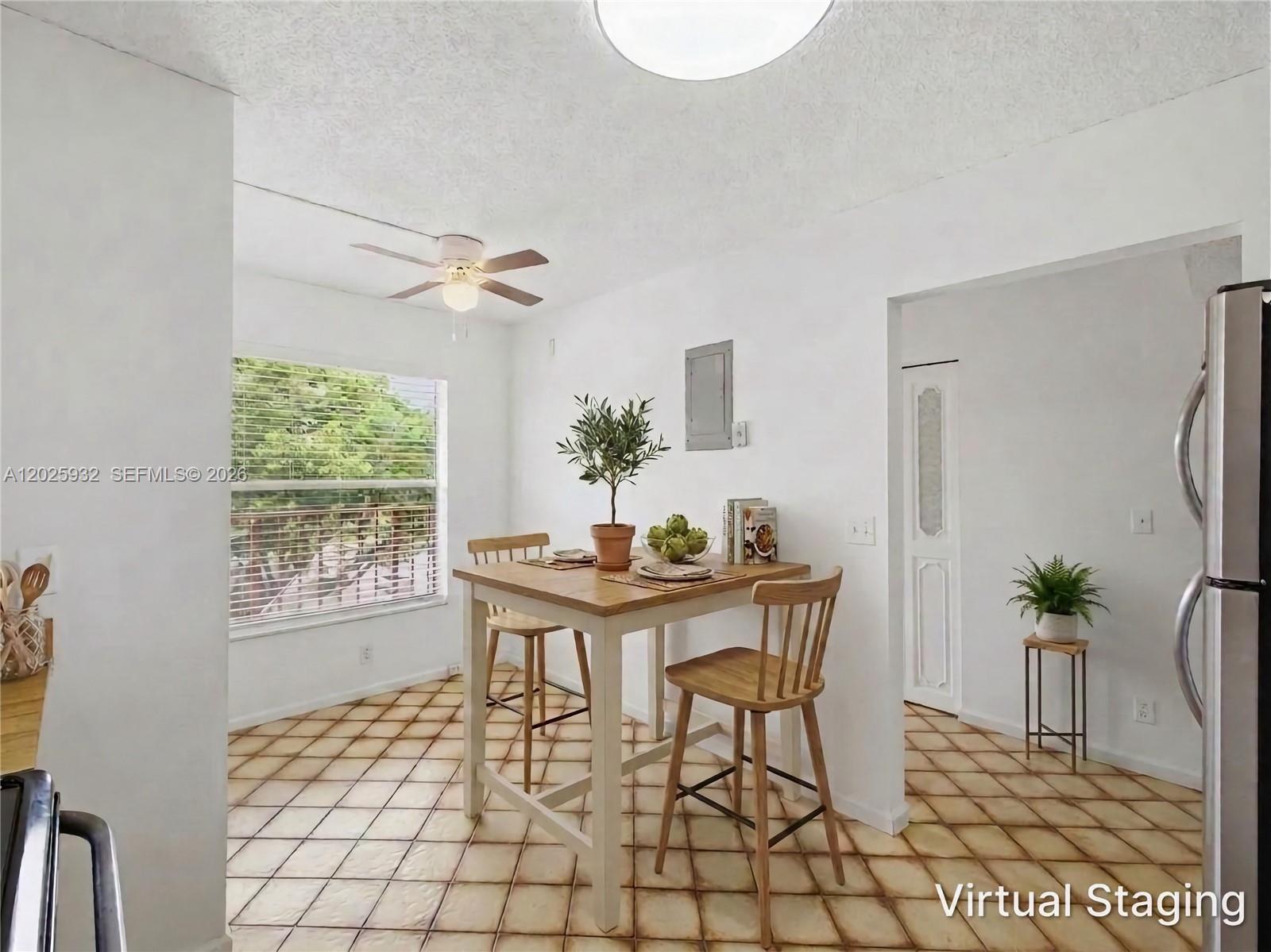 A dining area features a wooden table with two chairs, tiled flooring, and a window — 14623 Bonaire Blvd # 405, Delray Beach FL 33446, DELRAY BEACH, FL