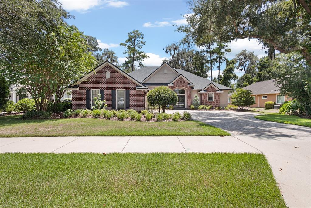 A single-story brick house with a paved driveway and a manicured lawn — 13573 NW 8TH ROAD, NEWBERRY, FL