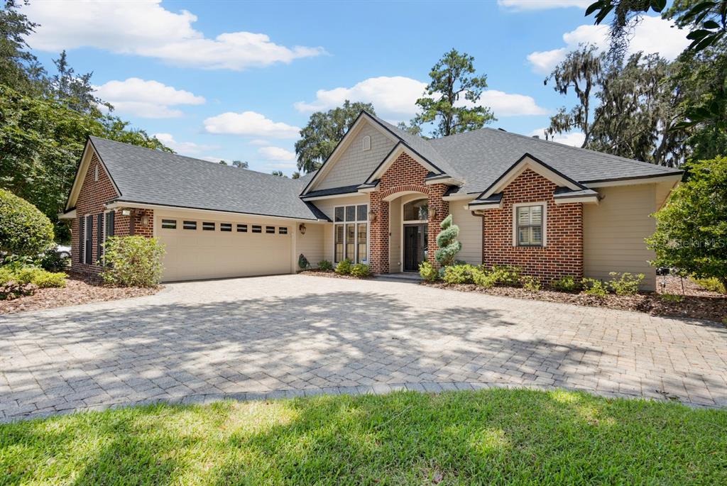 A single-story brick and siding house with a paved driveway and a three-car garage — 13573 NW 8TH ROAD, NEWBERRY, FL