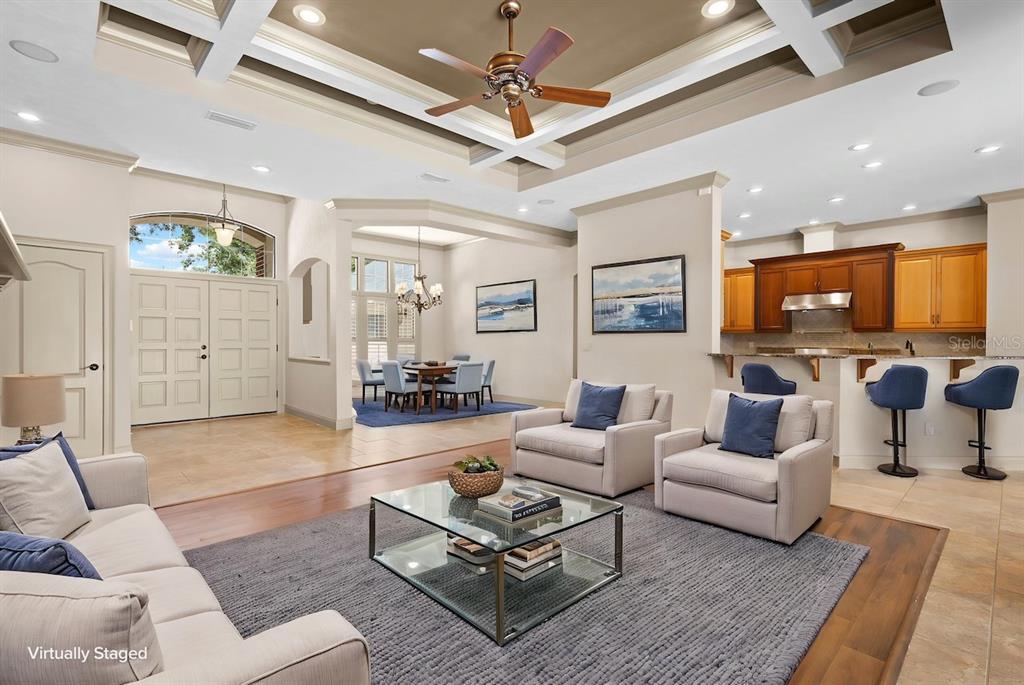 An open-concept living room features a coffered ceiling, hardwood floors, and an adjacent kitchen area — 13573 NW 8TH ROAD, NEWBERRY, FL