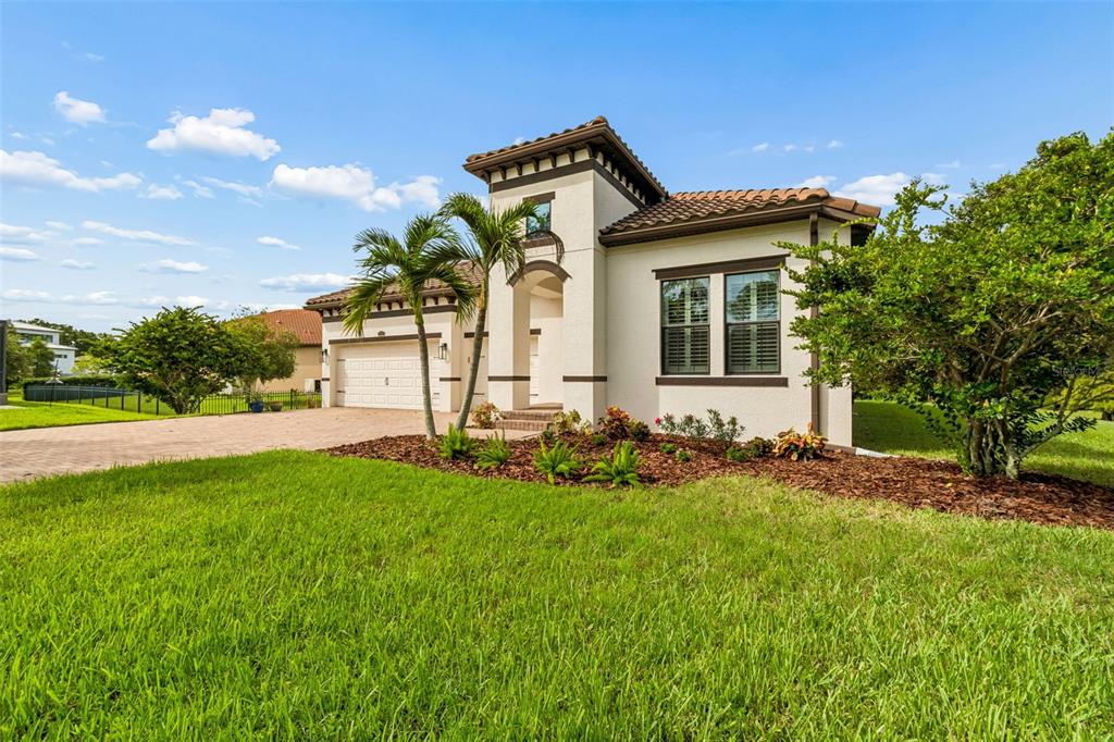 A single-story stucco house with a tile roof, two-car garage, and palm trees in front — 7872 MARSH POINTE DRIVE, TAMPA, FL