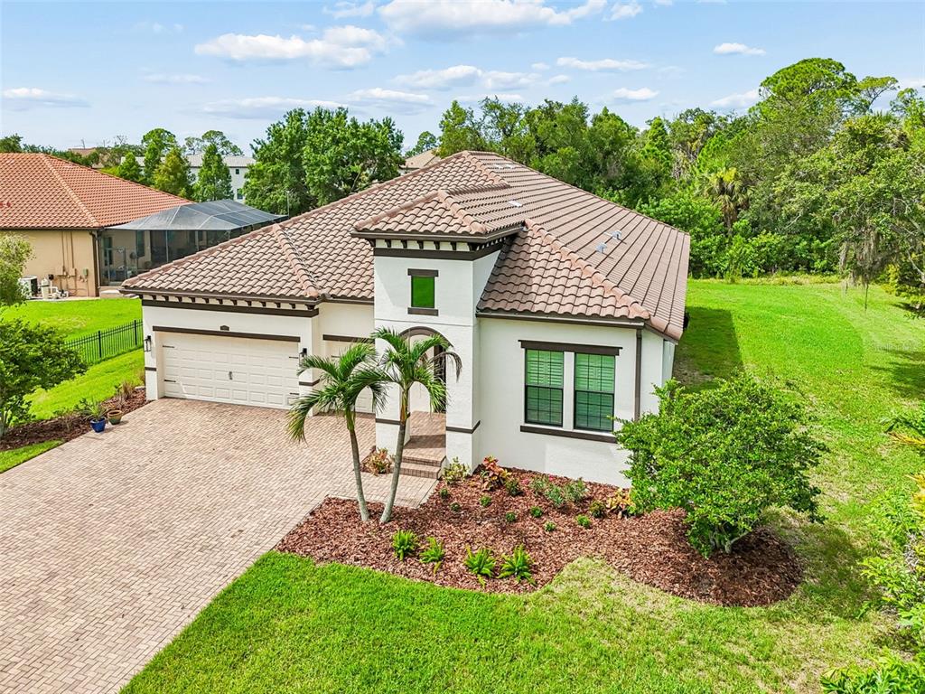 A single-story house with a tiled roof, a two-car garage, and a brick paver driveway — 7872 MARSH POINTE DRIVE, TAMPA, FL