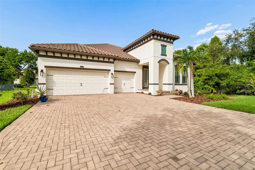 A single-story house with a tiled roof, two garage doors, and a paved driveway — 7872 MARSH POINTE DRIVE, TAMPA, FL