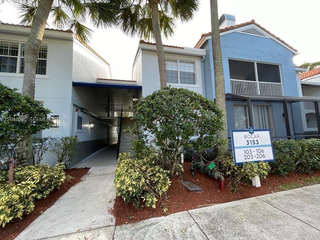 The exterior of a two-story residential building features a covered walkway and landscaping — 3153 Clint Moore Rd # 106, Boca Raton FL 33496, BOCA RATON, FL