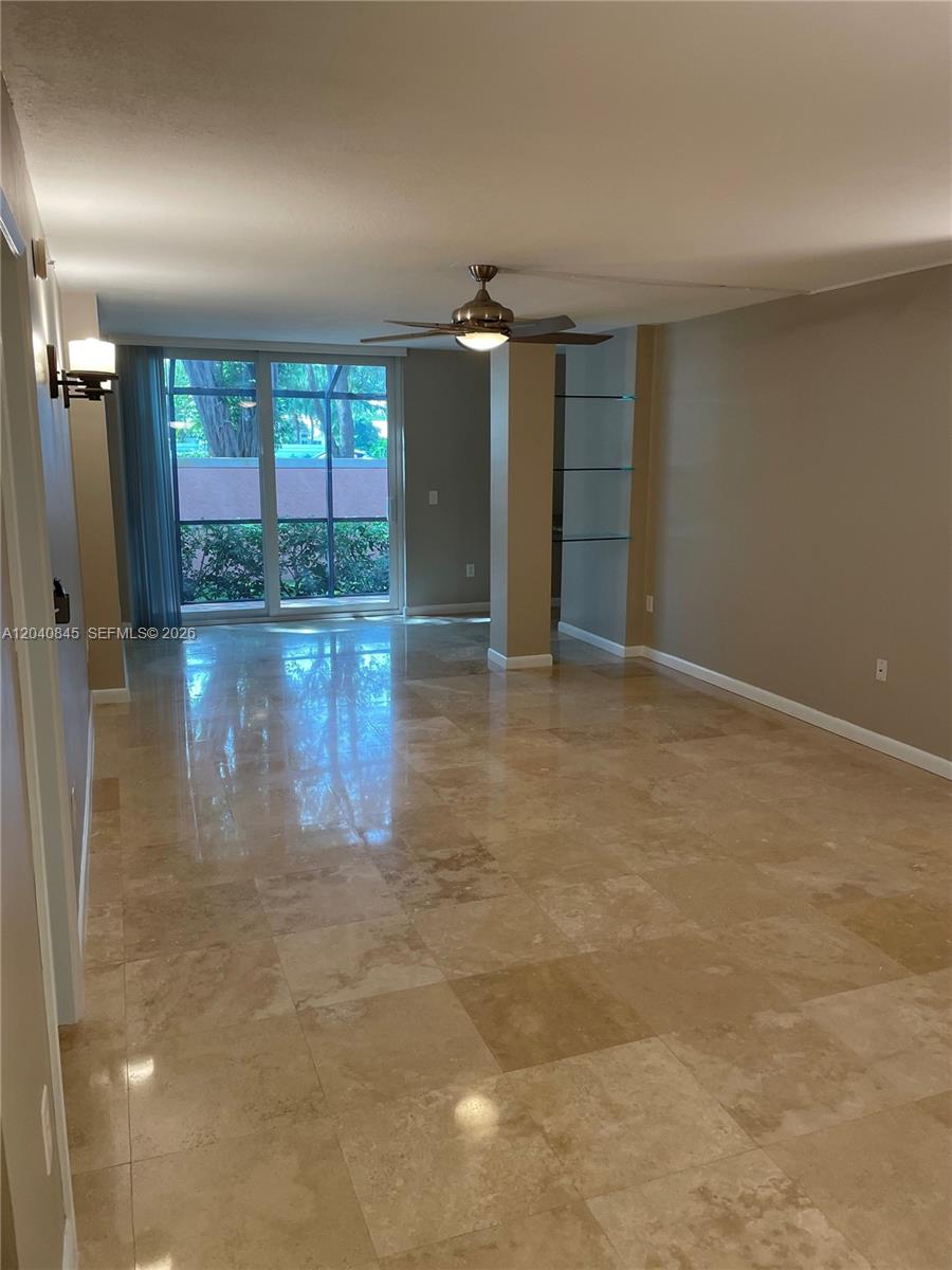 An empty living room features beige tile flooring, a ceiling fan, and sliding glass doors — 3153 Clint Moore Rd # 106, Boca Raton FL 33496, BOCA RATON, FL