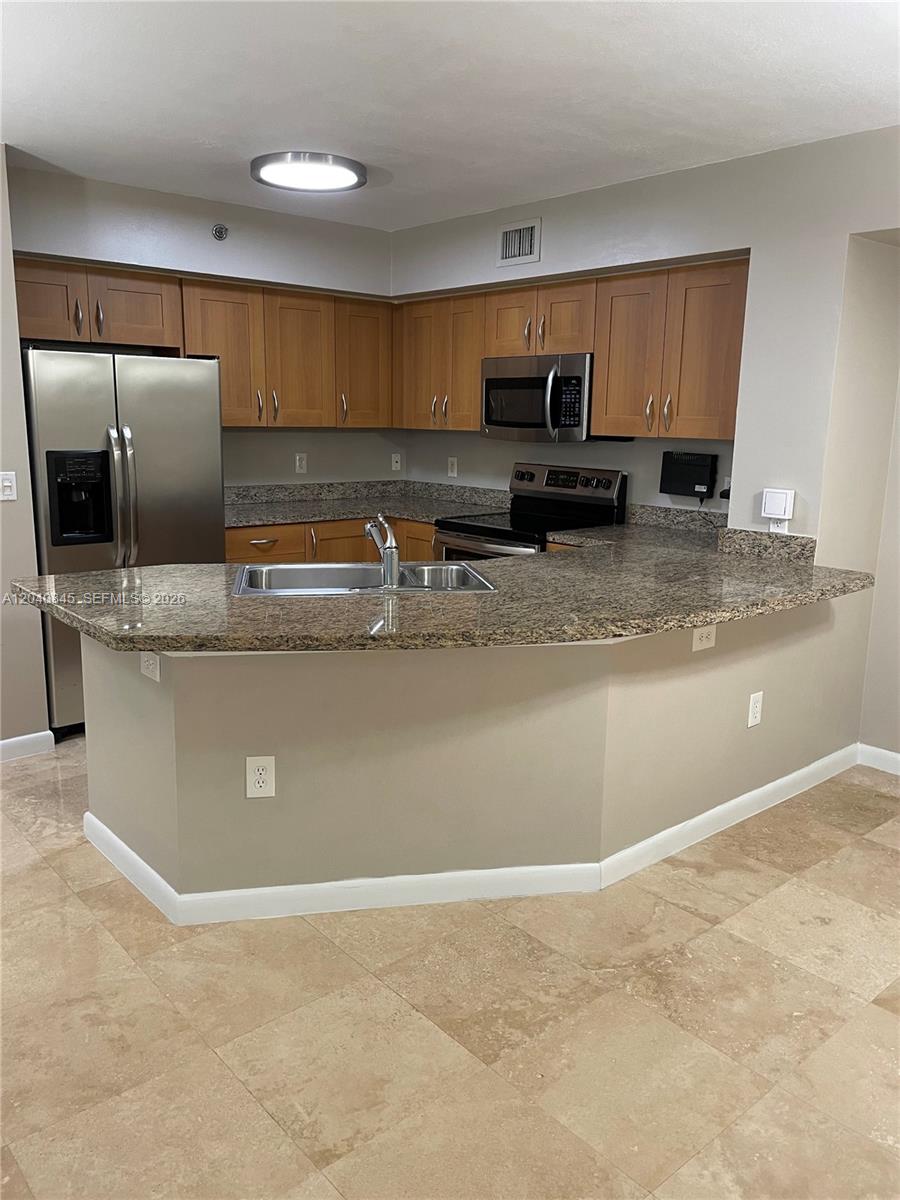 A kitchen features wood cabinets, granite countertops, stainless steel appliances, and a breakfast bar — 3153 Clint Moore Rd # 106, Boca Raton FL 33496, BOCA RATON, FL