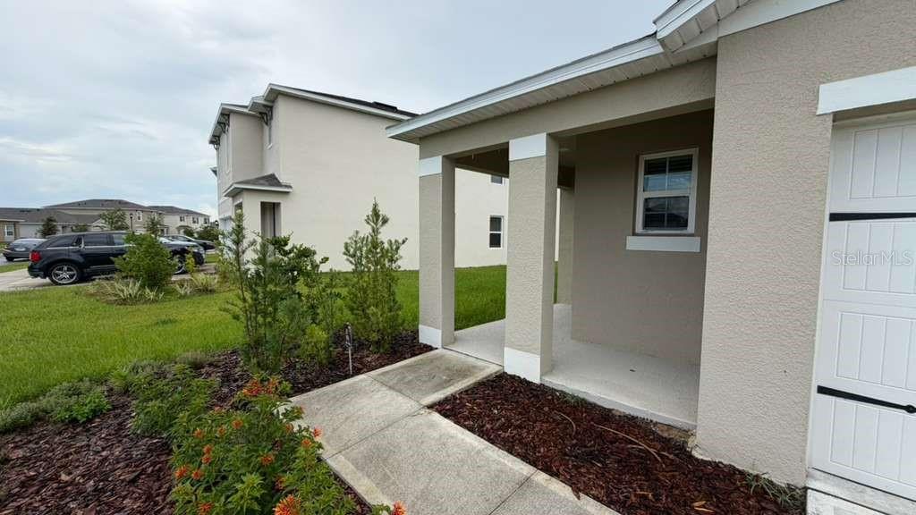 A concrete walkway leads to the covered front porch of a tan stucco house — 1511 CATBRIAR WAY, DAVENPORT, FL