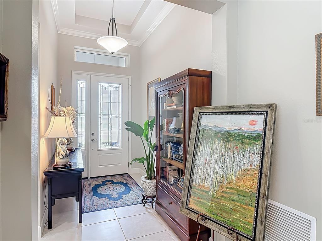 A foyer features a white front door, a wooden cabinet, a painting, and tile flooring — 1169 AVERY MEADOWS WAY, DELAND, FL