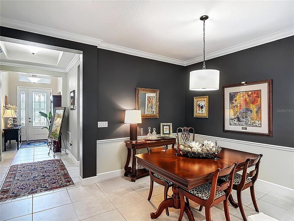 A dining room features dark gray walls, a wooden table, and a view into the entryway — 1169 AVERY MEADOWS WAY, DELAND, FL