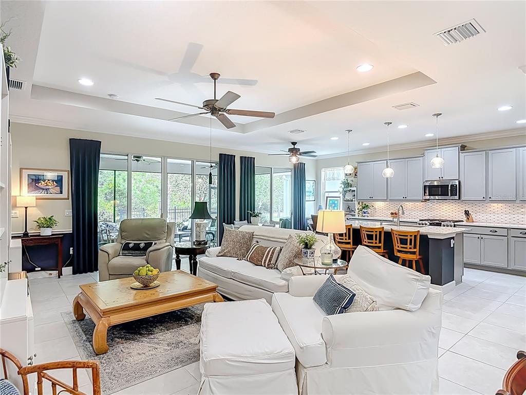 An open-concept living room and kitchen featuring light cabinetry, tile floors, and sliding glass doors — 1169 AVERY MEADOWS WAY, DELAND, FL