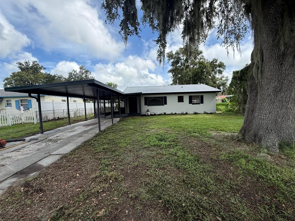A single-story house with a metal roof and a large attached carport sits on a lawn — 430 LUCILLE STREET, BARTOW, FL