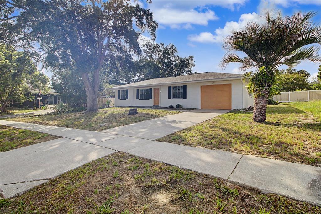 A single-story white house with a garage and a palm tree in the front yard — 12368 MAYBERRY ROAD, SPRING HILL, FL