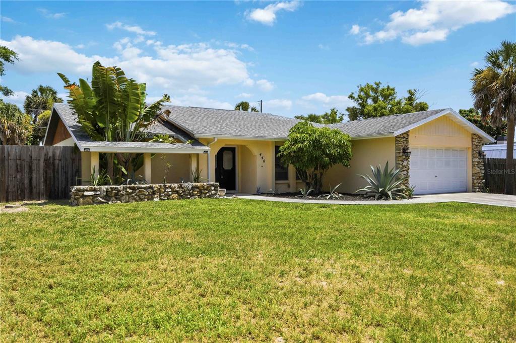 A single-story house with a yellow exterior, a stone planter, and a two-car garage — 440 LYCHEE ROAD, NOKOMIS, FL