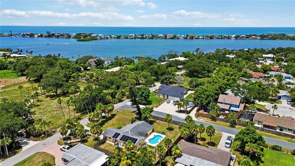 An aerial view shows residential houses with swimming pools near a bay and ocean — 440 LYCHEE ROAD, NOKOMIS, FL