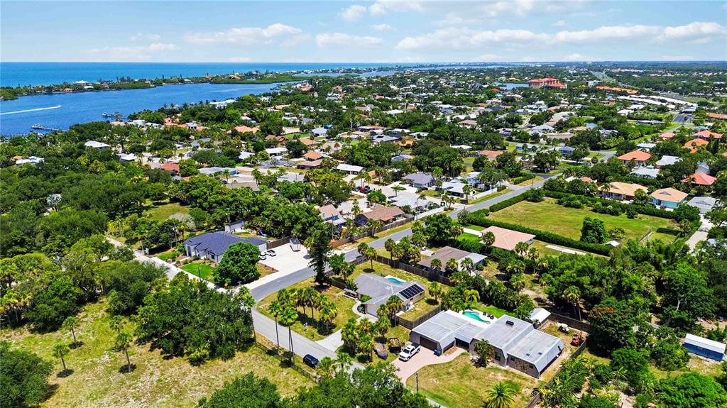 An aerial view shows a residential neighborhood near a body of water with lush trees — 440 LYCHEE ROAD, NOKOMIS, FL
